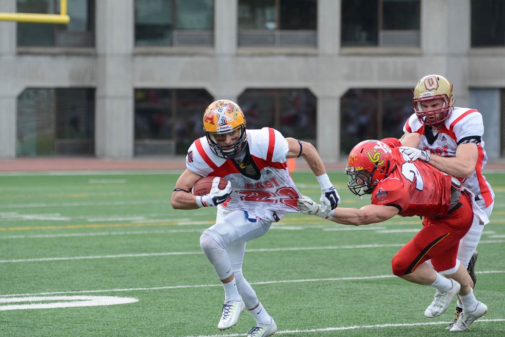 PHOTO CAPTION: Queen’s receiver Doug Corby (No. 23 in White) beats Calgary defensive back Hunter Turnbull (#28) en route to scoring one of his record three TDs in the 13th annual CIS East-West Bowl, which serves as the CFL prospects game. PHOTO CREDIT: Simon Poitrimolt, courtesy McGill Athletics & Recreation